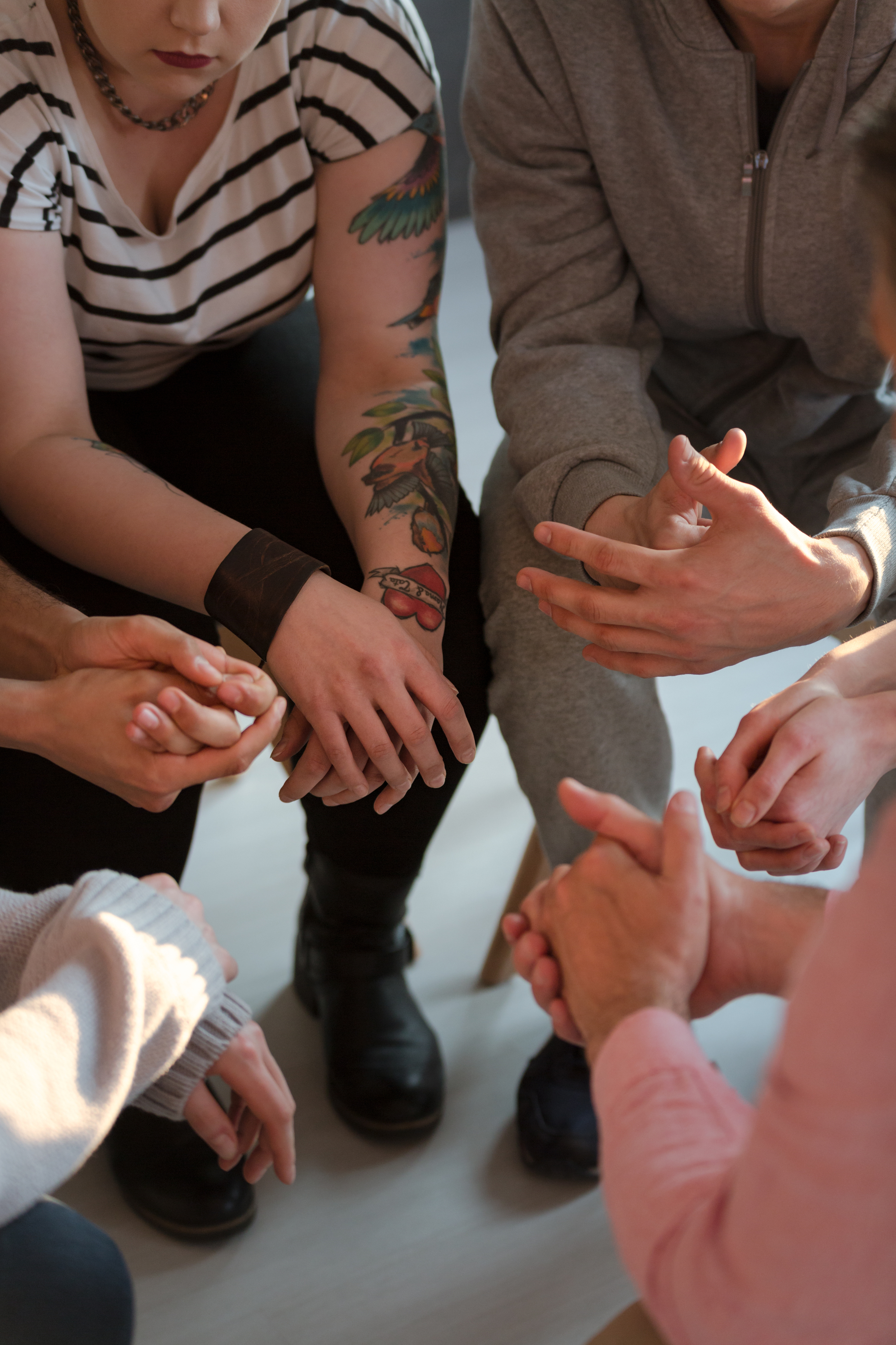 Young people with tattoos sitting in a circle during meeting of support group